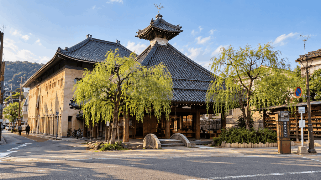 Satono-yu public bath building with tiled roof and willow trees in Kinosaki Onsen