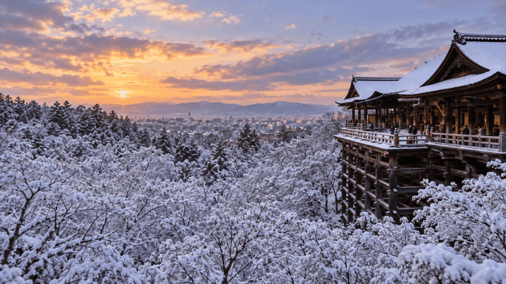 Kiyomizudera Temple overlooking snow-covered Kyoto at sunset, with its wooden terrace surrounded by snowy trees