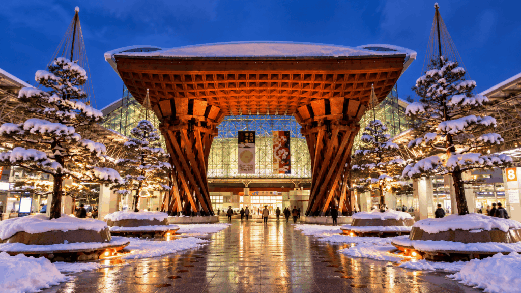 Snow-covered Tsuzumi-mon Gate illuminated at Kanazawa Station on a winter evening