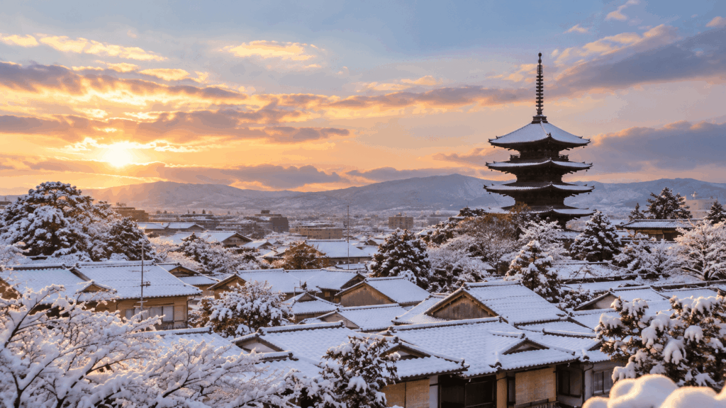 Yasaka Pagoda rising above snow-covered traditional rooftops in Kyoto's Higashiyama district at sunset