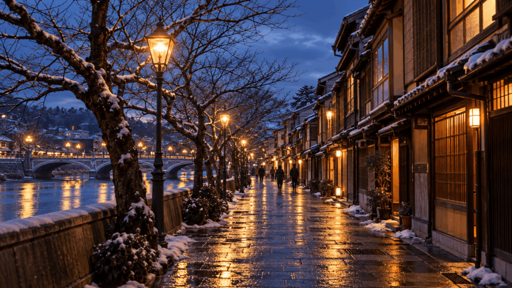 Snow-covered traditional wooden teahouses along the Asano River in Kanazawa's Kazuemachi Chaya District at dusk