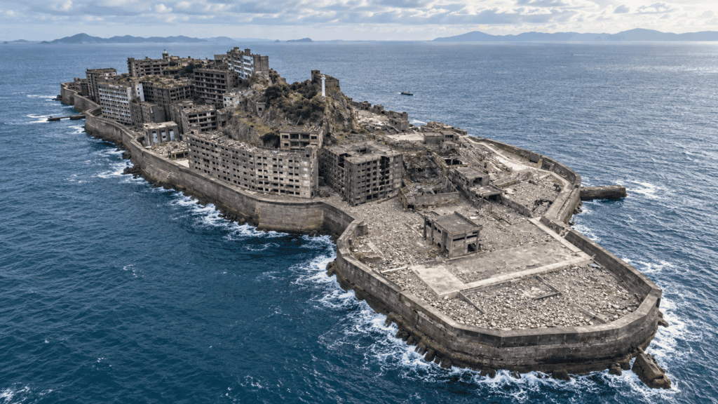 Aerial view of Gunkanjima Island in Nagasaki, with ruined apartment blocks and seawalls extending into the ocean