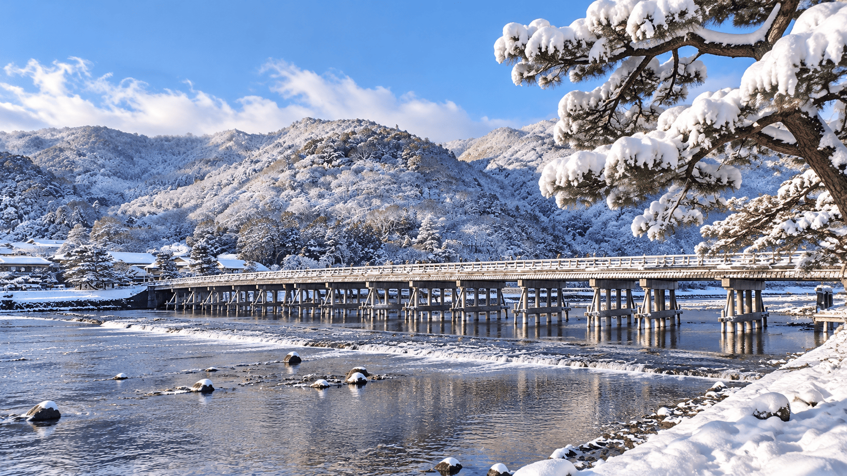 Togetsukyo Bridge crossing the Katsura River beneath snow-covered mountains in Arashiyama, Kyoto