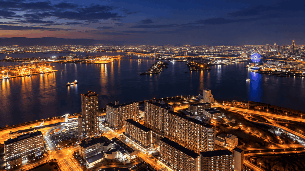 Panoramic night view of Osaka Bay with illuminated bridges, waterfront buildings, and the Osaka skyline