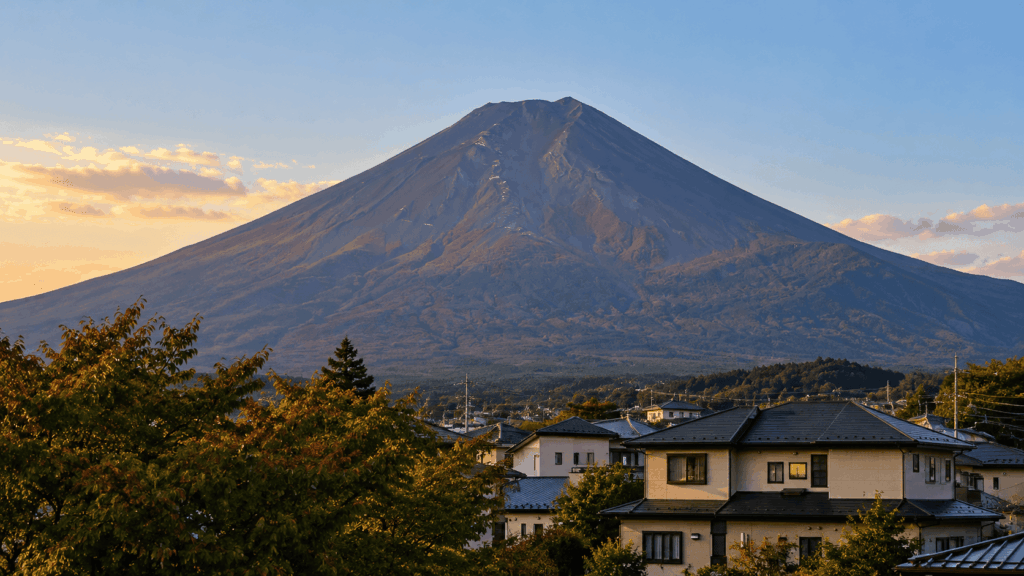 Mount Fuji without its first autumn snowfall rising above residential houses near Kofu at sunset in October