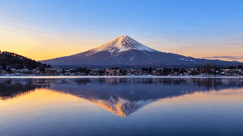 Snow-capped Mount Fuji reflected in the calm waters of Lake Kawaguchi during a colorful January sunrise