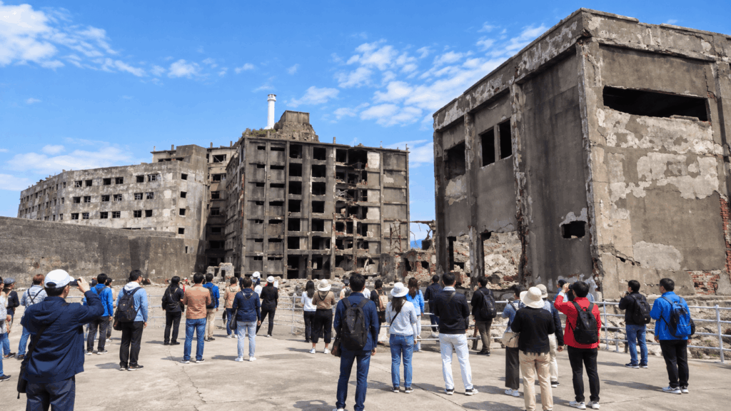 Tourists exploring the ruins of Gunkanjima Island during a guided landing tour in Nagasaki, Japan