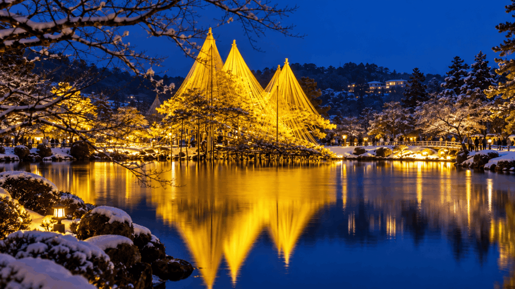 Illuminated yukitsuri snow-support ropes reflected in a pond at Kenrokuen Garden in Kanazawa on a snowy winter night