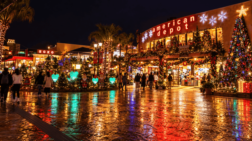 Christmas trees and colorful holiday illuminations reflecting on wet pavement at Mihama American Village in Okinawa at night