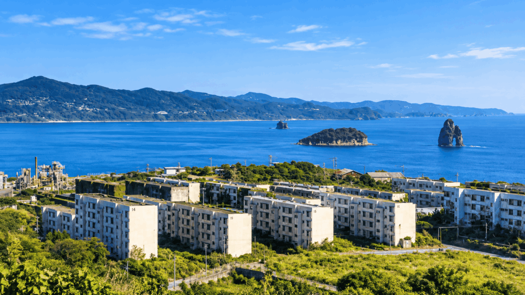 Abandoned apartment blocks surrounded by greenery on Ikeshima Island, overlooking the blue sea near Nagasaki