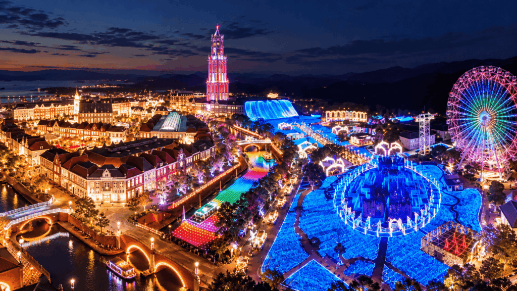 Illuminated Huis Ten Bosch theme park at night in Nagasaki, with colorful lights, a Ferris wheel and European-style buildings
