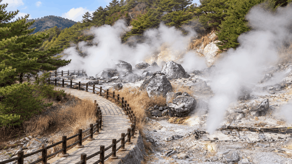 Wooden walking path winding through steaming volcanic vents and rocky terrain at Unzen Jigoku in Nagasaki, Japan