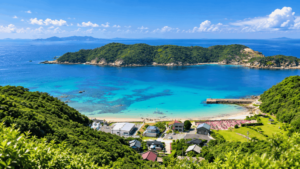 Panoramic view of a turquoise bay, sandy beach, and lush green islands in the Goto Islands of Nagasaki, Japan