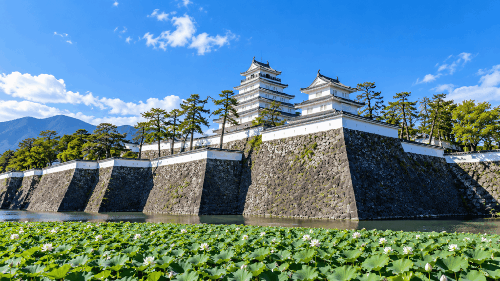 White towers of Shimabara Castle rising above stone walls and a lotus-filled moat in Shimabara, Nagasaki