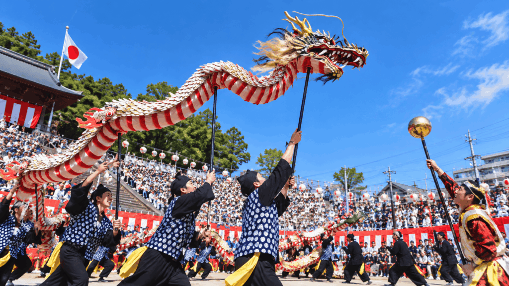 Traditional dragon dance performance at the Nagasaki Kunchi Festival, with performers carrying a colorful dragon before a large crowd