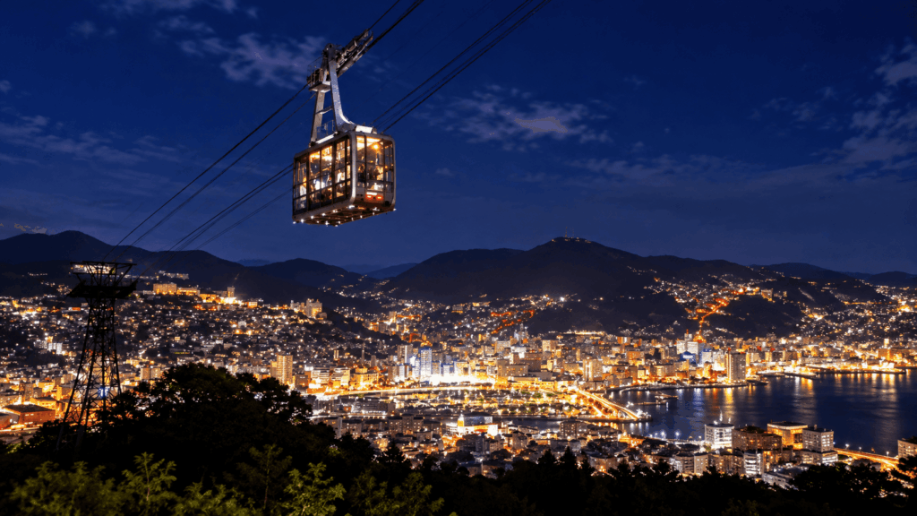 Nagasaki Ropeway cable car overlooking the illuminated city and harbor at night from Mount Inasa in Nagasaki, Japan