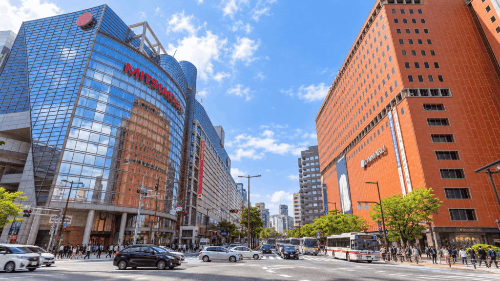 Busy intersection in Tenjin, Fukuoka, with the Mitsukoshi and Daimaru department stores, buses, and pedestrians